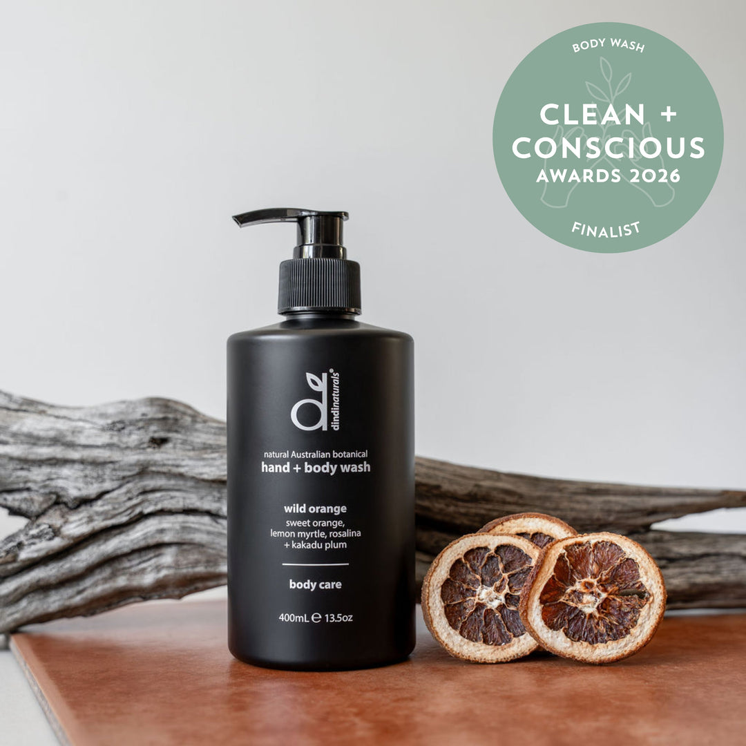Black body wash bottle with pump on a wooden surface, featuring 'Clean + Conscious' awards badge.
